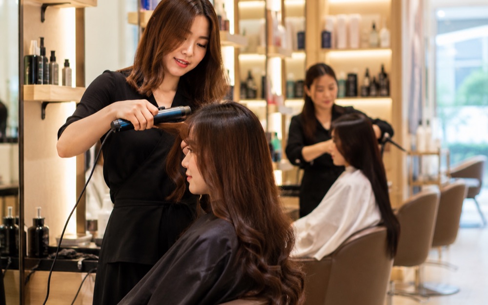 A stylist styling a client’s hair at a salon station